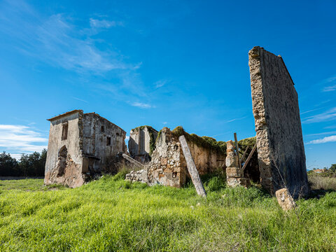 Ruins of an abandoned stone farmhouse in a green field under a c
