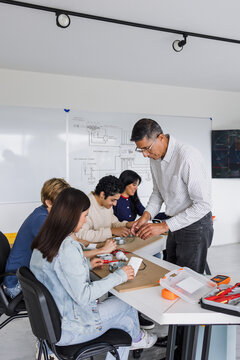 latino senior professor of electricity class with group of mexican students in electrical circuits workshop at university in Mexico Latin America
