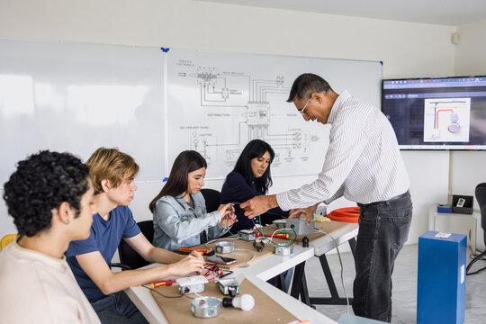latino senior professor of electricity class with group of mexican students in electrical circuits workshop at university in Mexico Latin America