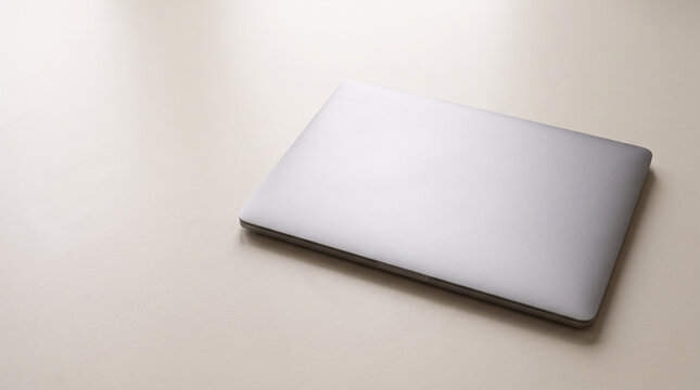 Photorealistic Slim White Laptop Computer with Closed Lid on a Soft Beige Surface, Minimalist Modern Technology Product for Business and Digital Workspace Advertising