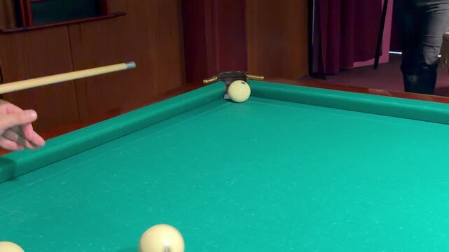 Man aiming cue at white billiard ball on green felt table in Russian billiards game indoors, player missing corner pocket shot, traditional sports leisure activity, pool room background.