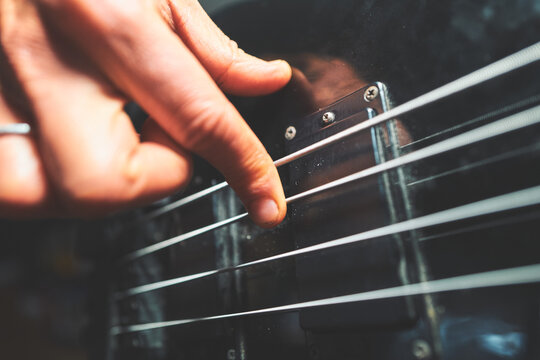 Extreme Close-Up of Fingers Plucking Strings Over a Bass Pickup