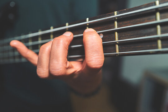Close-Up of a Woman Fretting a Note on a Bass Guitar