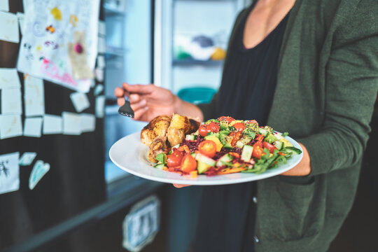 Woman Holding a Fork Over a Plate of Chicken and Salad