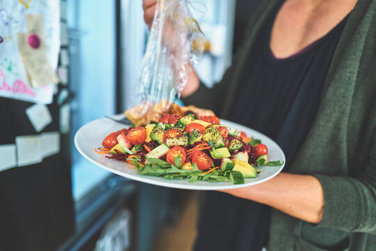 Woman Removing Plastic Wrap from a Plate of Fresh Salad