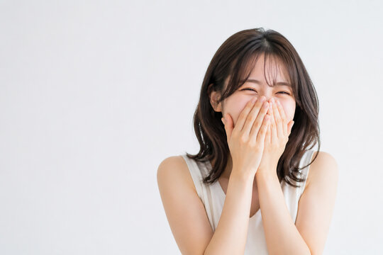 口元を両手で覆って笑う日本人女性