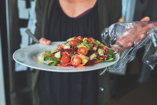 Woman Holding a Plate of Fresh Vegetable Salad with Plastic Wrap