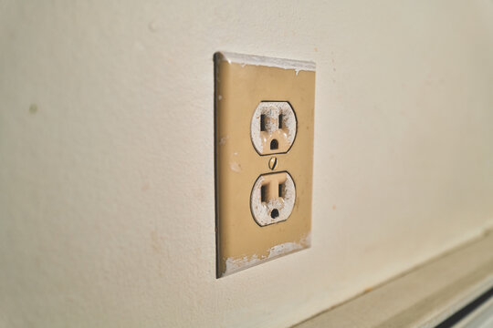 Old Yellowed Electrical Outlet on a Painted Wall
