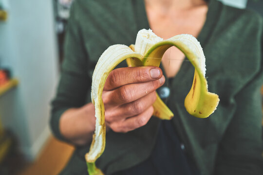 Woman Holding a Half-Peeled Banana in Front of Her