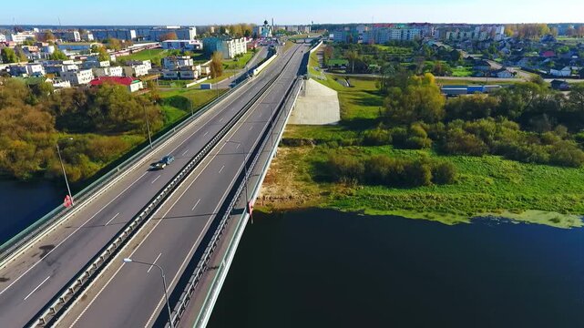 Highway river crossing small town. Aerial flyover cars autumn church skyline.