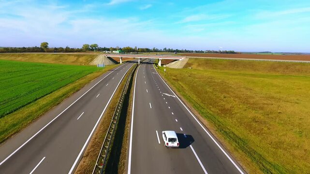 Cars driving under overpass bridge. Drone flight traffic truck road farmland.