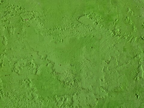 Bright green textured plaster wall background with rough uneven surface, raised ridges, natural imperfections, and subtle shadows