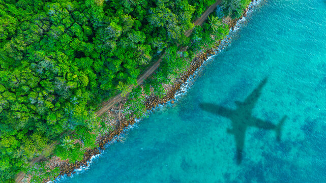 Aerial view of shadow passenger plane silhouette and sandy beach blue sea with waves at sea beach summer vacation sea travel concept	