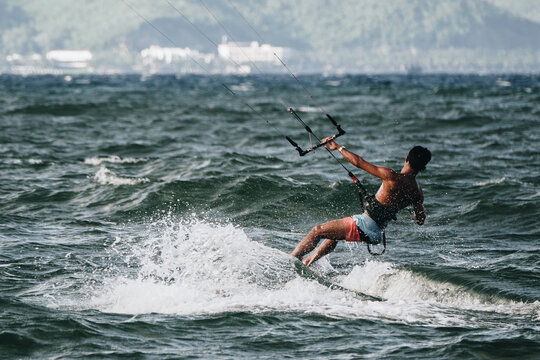 Asian Vietnamese athlete male kitesurfer kitesurfing on sea waves in windy weather near the coast of Nha Trang in Vietnam in Asia