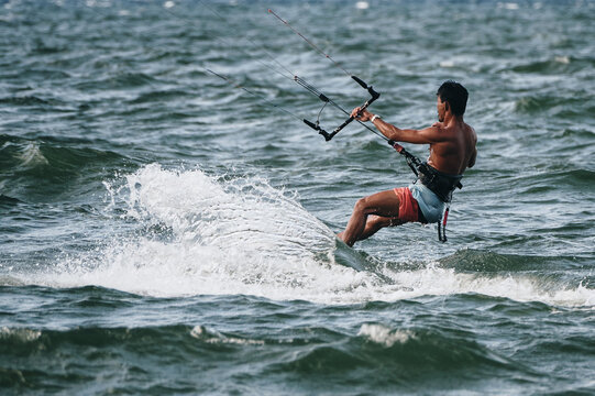 Asian man kitesurfer kitesurfing on sea waves in windy weather near the coast of Nha Trang in Vietnam in Asia