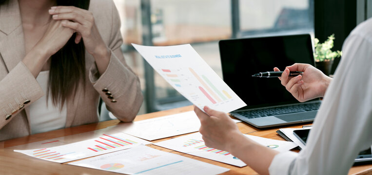 Over the Shoulder View of Businesswomen Analyzing Financial Reports in Office Meeting