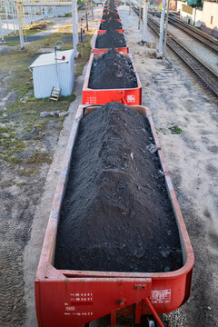 Freight train cars loaded with mined copper ore standing on tracks at an industrial site.