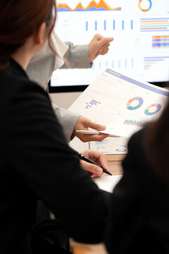 Vertical Over the Shoulder View of Businesswomen Analyzing Financial Reports in Office