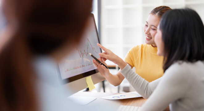 Asian Businesswomen Smiling and Pointing Pen at Tablet in Office Meeting