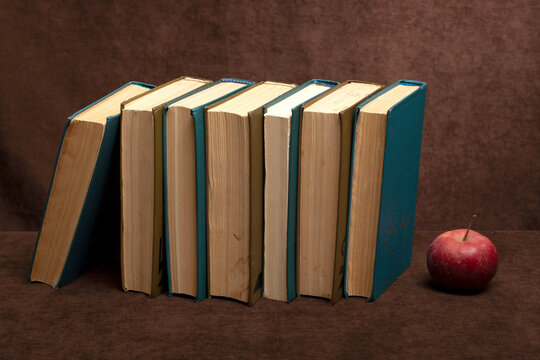 Still life with a stack of books on a table against a brown background