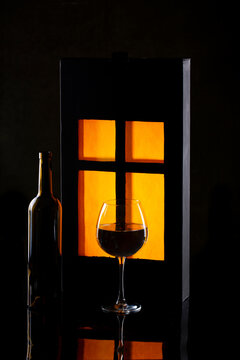A bottle and glass of wine against a glowing window