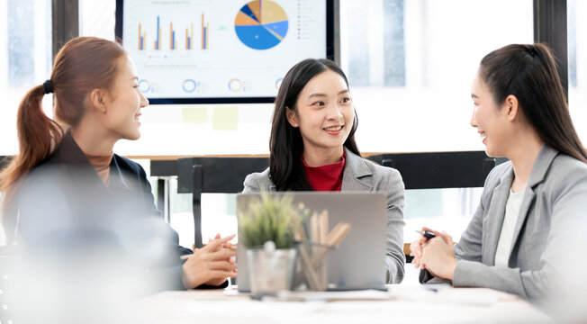 Asian Businesswomen Smiling and Discussing Work in Office Meeting
