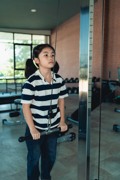 Young girl exercising with cable machine in modern gym focused on strength training and healthy lifestyle indoors