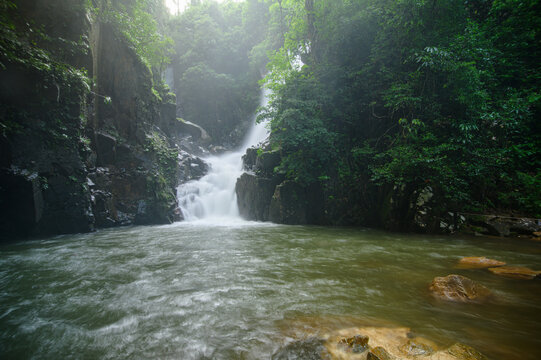 Tranquil forest waterfall cascading into river surrounded by lush greenery