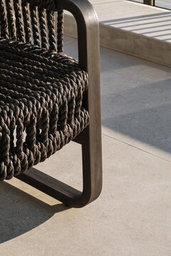 Woven outdoor lounge chair with dark rope seat and wooden frame on a warm modern terrace