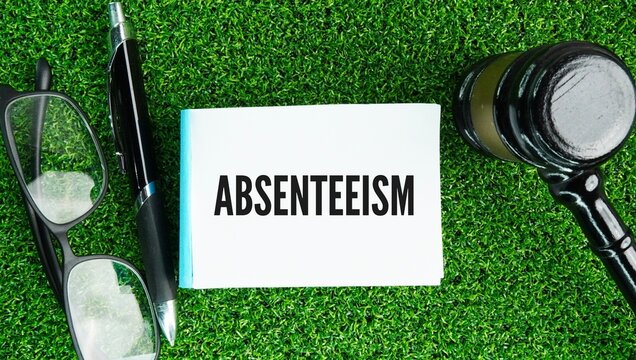 Judge's hammer, pen and paper with the word Absenteeism is a habitual pattern of unplanned or unexcused absence from work, school, or another duty without a valid reason.