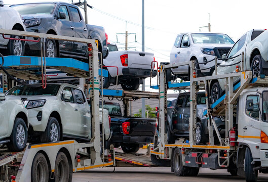 Car carrier trailers loaded with new pickup trucks for delivery from factory to dealership, with vehicles arranged on upper and lower decks for automotive logistics, road freight and distribution