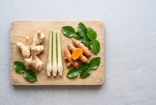 Fresh galangal, lemongrass and turmeric on a wooden board