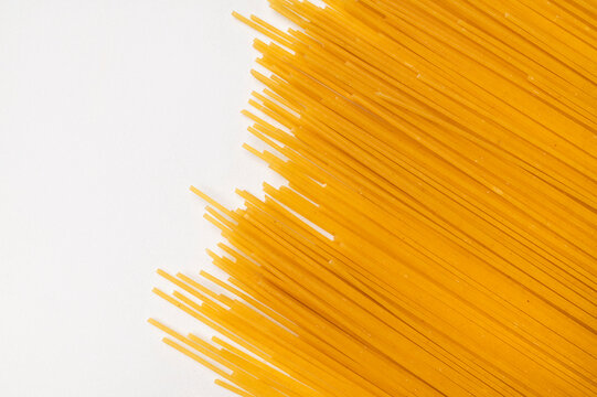 Dry spaghetti on light gray background creates golden contrast with generous copy space, ideal for pasta packaging, food advertising, culinary promotions and minimalist commercial design projects.