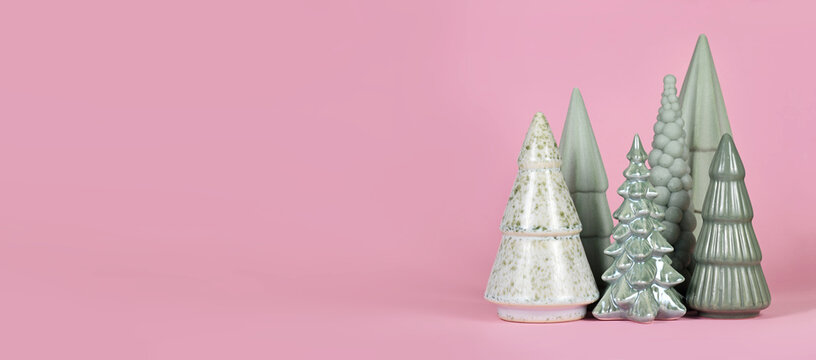 Different shaped light green ceramic Christmas trees on pink background