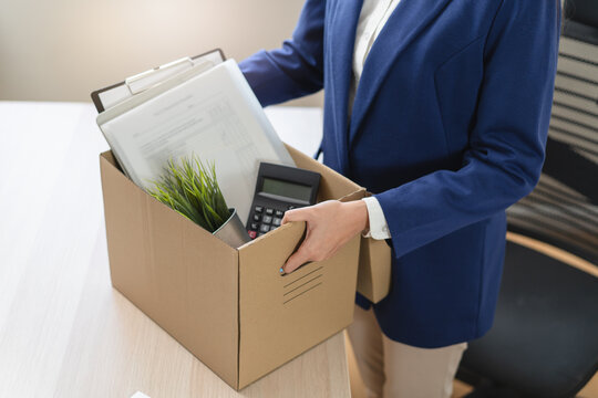Close-up of a businessman holding a cardboard box with personal belongings after resignation.