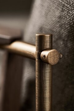 Patinated bronze floor lamp hinge with brushed metal texture and adjustment screw in quiet luxury living room. Detailed hardware accent for interior design projects