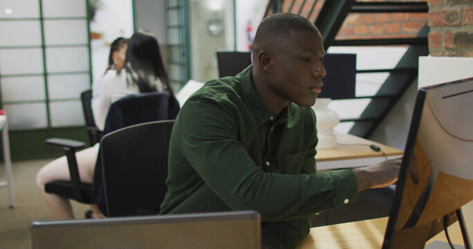 Happy african american businessman using laptop at office