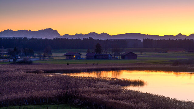 Sunset over Fohnsee lake with mountains and rural barns
