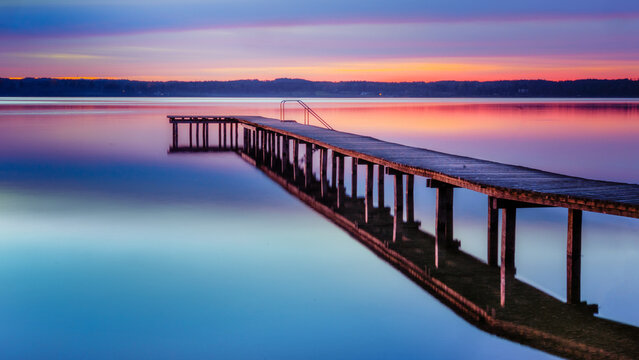Jetty on Lake Starnberg at sunset with mountain view