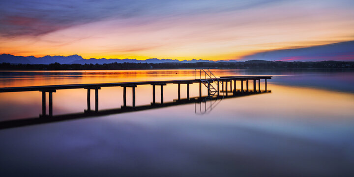Jetty on Lake Starnberg at sunset with mountain views