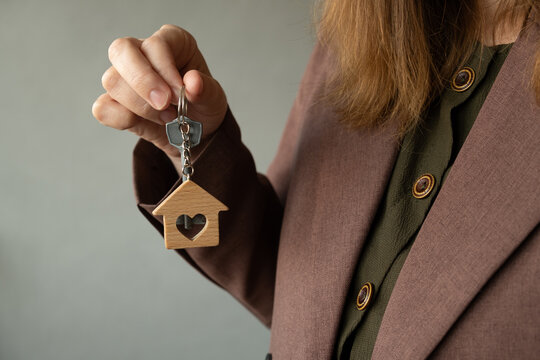 Buying or renting real estate. Woman with the keys to her new home, ready to move in, standing against a gray wall.