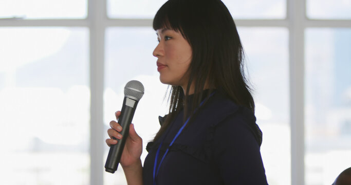 Portrait of focused asian businesswoman holding microphone with copy space in office