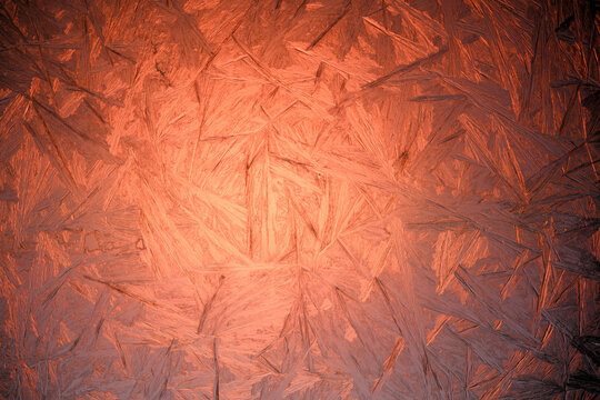 Frozen pattern on window glass. Sunrise light glowing throuth icy window. Real texture of winter snowfrost. Christmas background