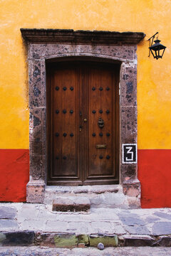 Wooden door framed by stone doorway on colorful wall, mexico
