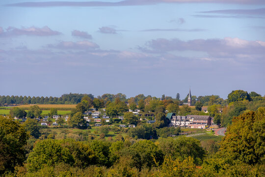 The terrain hilly countryside with houses and green grass meadow under blue sky in Autumn, Noorbeek is a village in the Dutch province of Limburg, The municipality of Eijsden-Margraten, Netherlands.