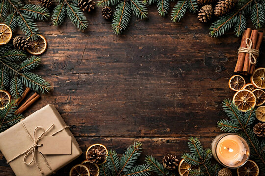 Warm Cinnamon and Pine Christmas Flat Lay Frame on Dark Rustic Wood with Kraft Gift Candle Dried Orange and Pinecones