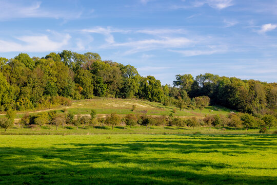 The terrain hilly countryside with houses, green grass meadow under blue sky in late summer, Noorbeek is a village in the Dutch province of Limburg, The municipality of Eijsden-Margraten, Netherlands.