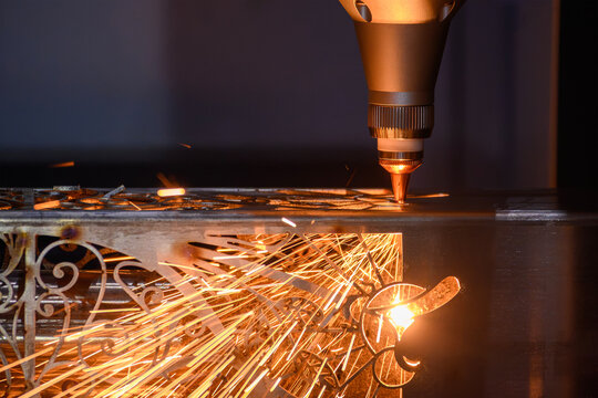 Close-up of a fiber laser cutting machine engraving and cutting a metal square pipe with sparks
