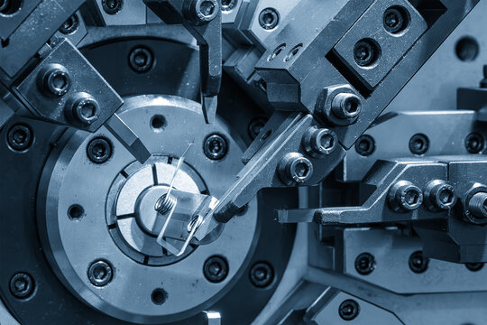 Wire coil spring mass production process by an automatic bending machine in a blue tone scene