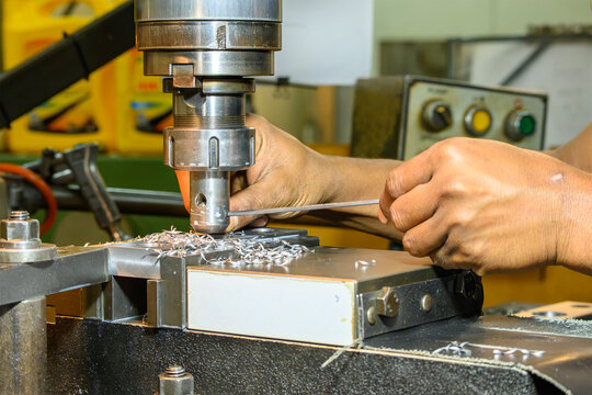 echnician adjusting and tightening the cutter on a milling machine with a metal wrench